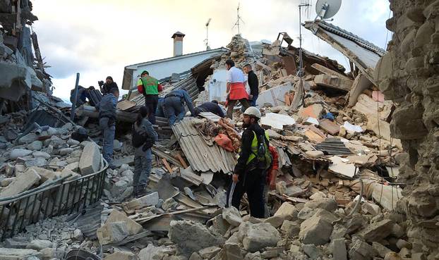 Rescuers work at a collapsed house following a quake in Amatrice