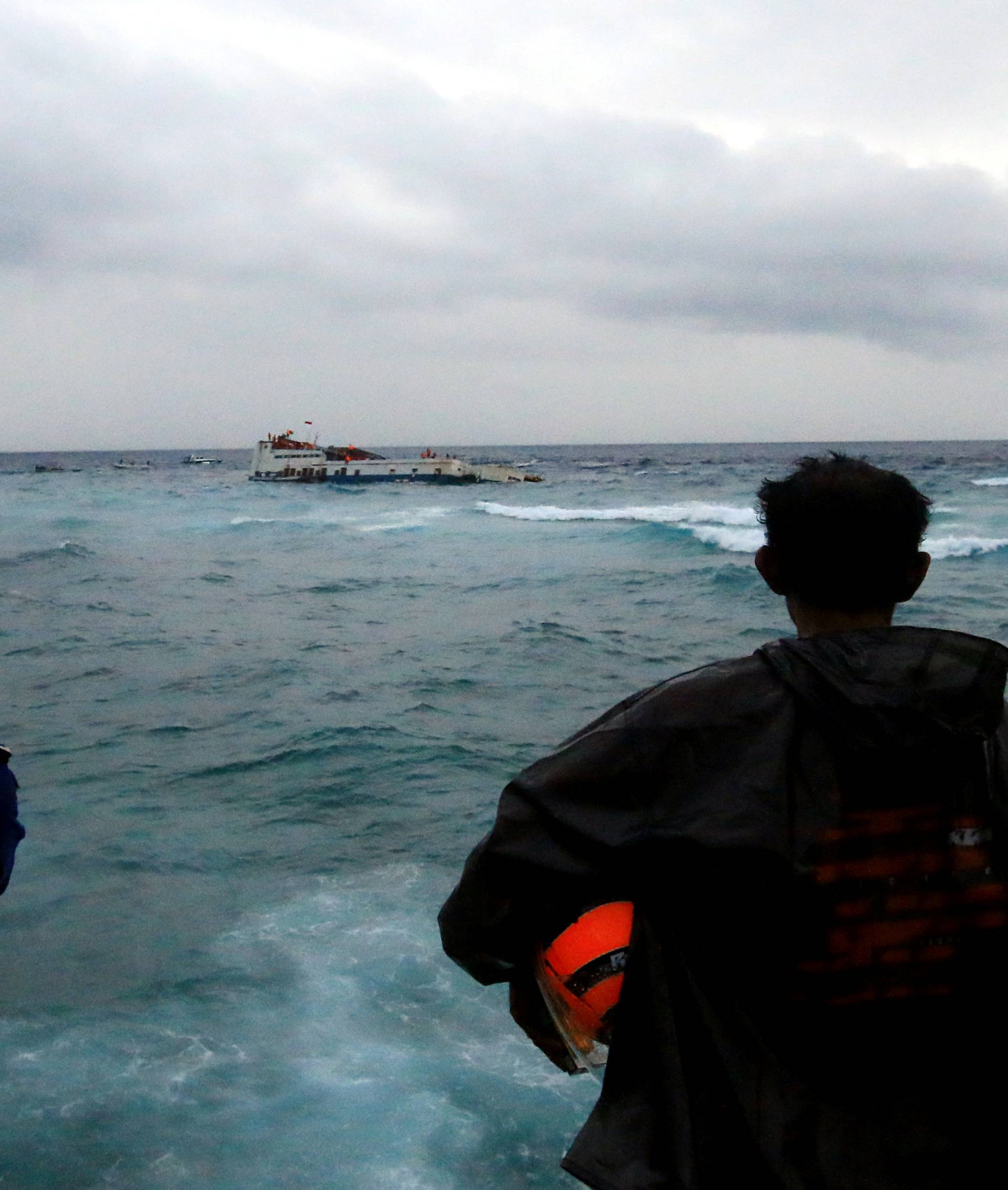 Villagers and officials stand as KM Lestari Maju boat sinks in the waters of Selayar island
