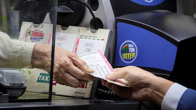 FILE PHOTO: Customer buys Powerball lottery ticket in New York