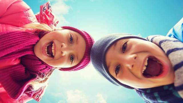 happy little boy and girl faces over blue sky