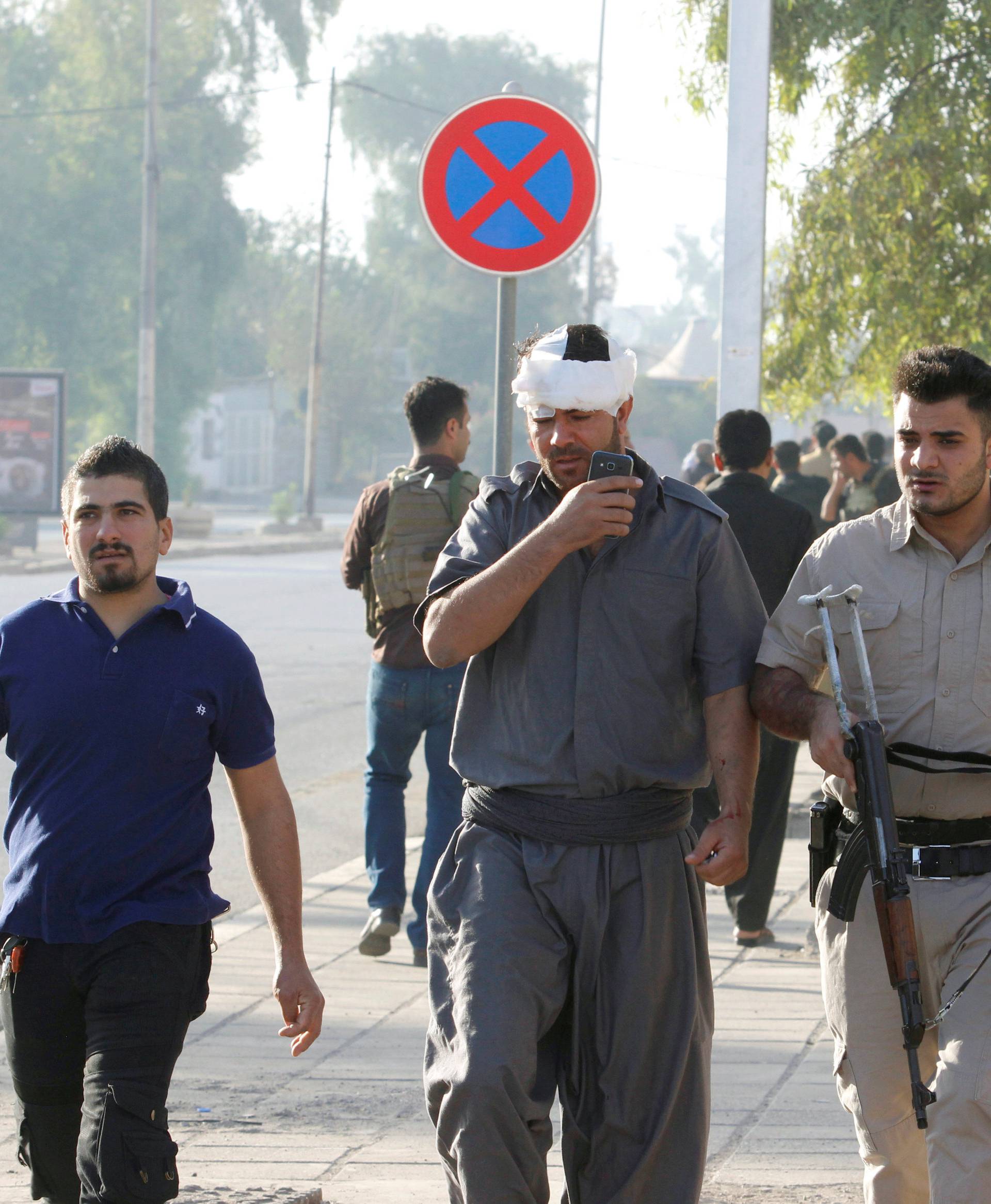An injured Kurdish man walks at a site of an attack by Islamic State militants in Kirkuk