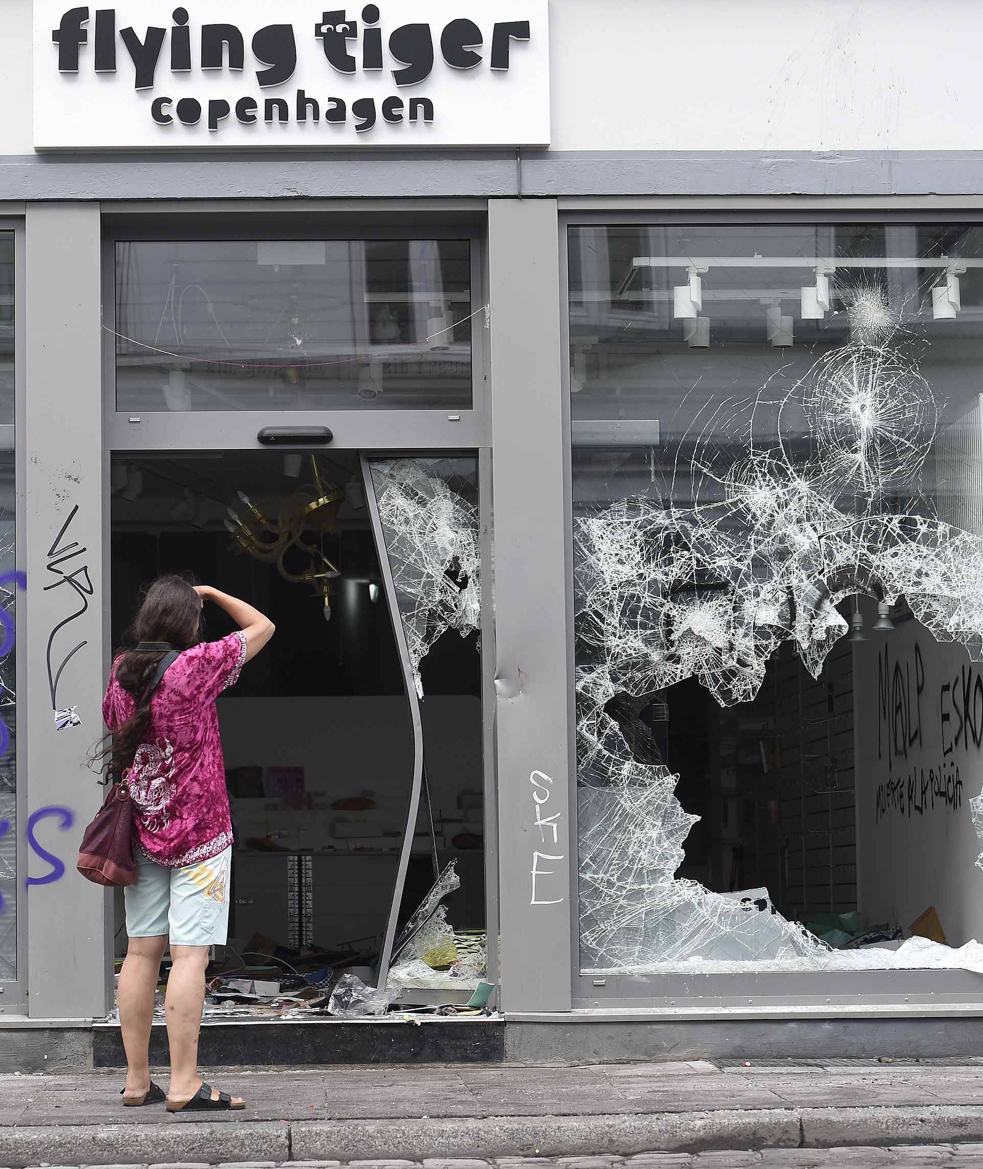 Woman takes pictures of a store, damaged after demonstrations at the G20 summit in Hamburg