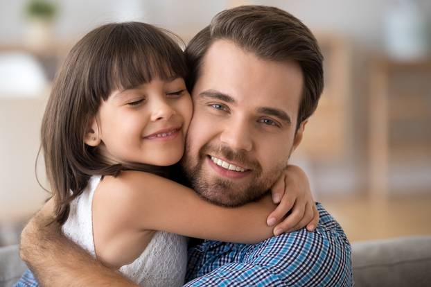 Portrait of cute little daughter hug young father