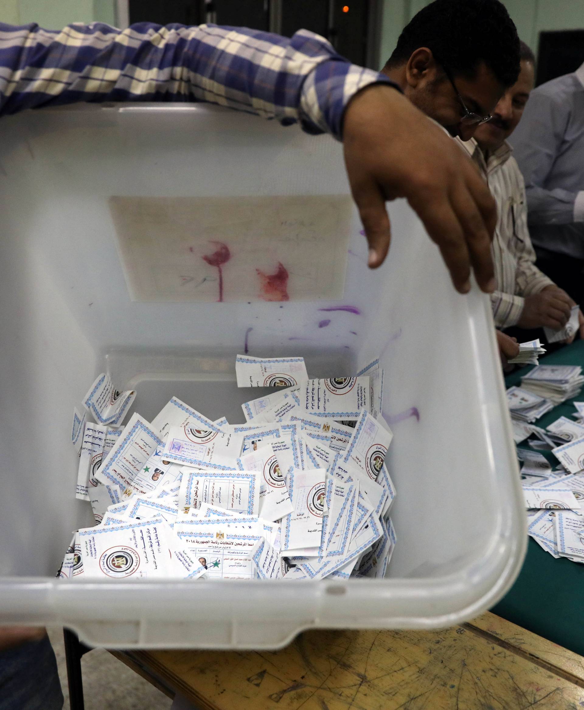 Man carries a ballot box as electoral workers sort ballots to count votes during the presidential election in Cairo