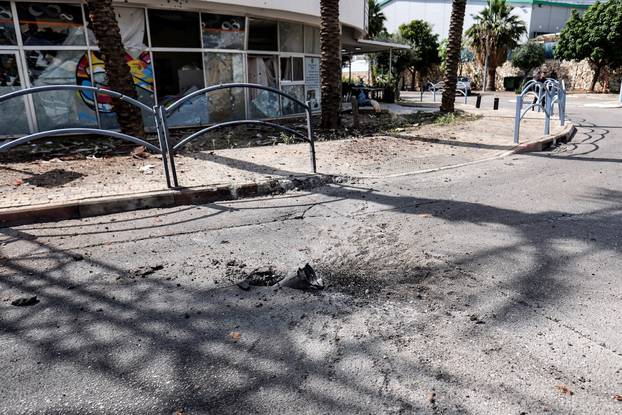 The remains of a rocket is seen stuck in the ground outside a damaged building of a bank in Shlomi