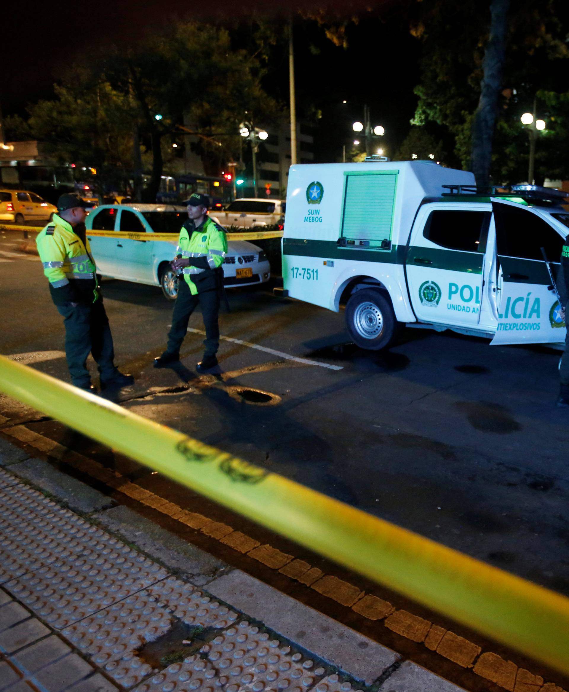 Police officers stand behind a yellow tape outside the Andino shopping center after an explosive device detonated in a restroom, in Bogota