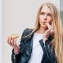 Beautiful young sexy woman eating a donut, licking her fingers taking pleasure a European city street. Outdoor. Warm color.