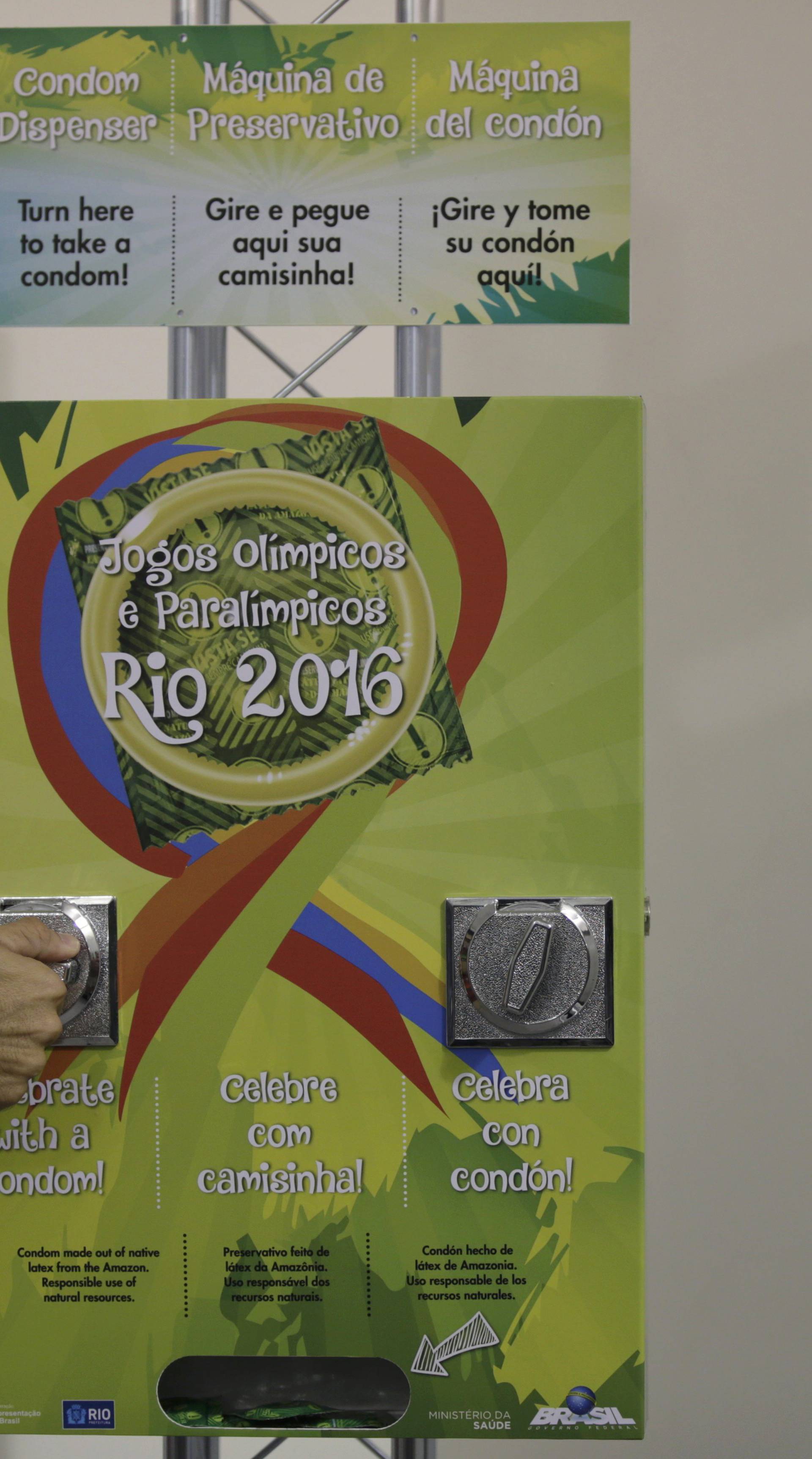  sports doctor demonstrates the operation of a condom dispenser inside the Olympic Village in Rio de Janeiro