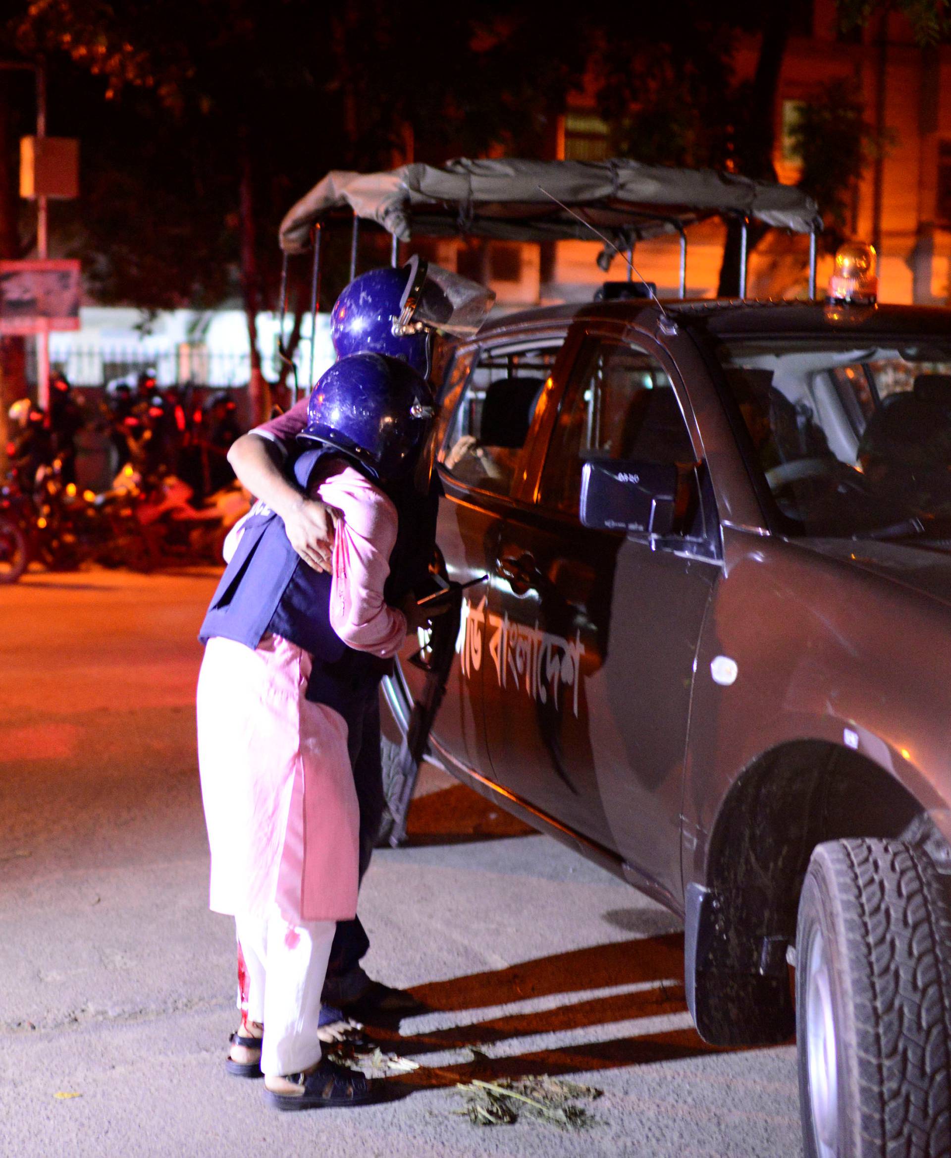 People try to help an injured person, after gunmen stormed the Holey Artisan restaurant and took hostages, in the Gulshan area of Dhaka, Bangladesh