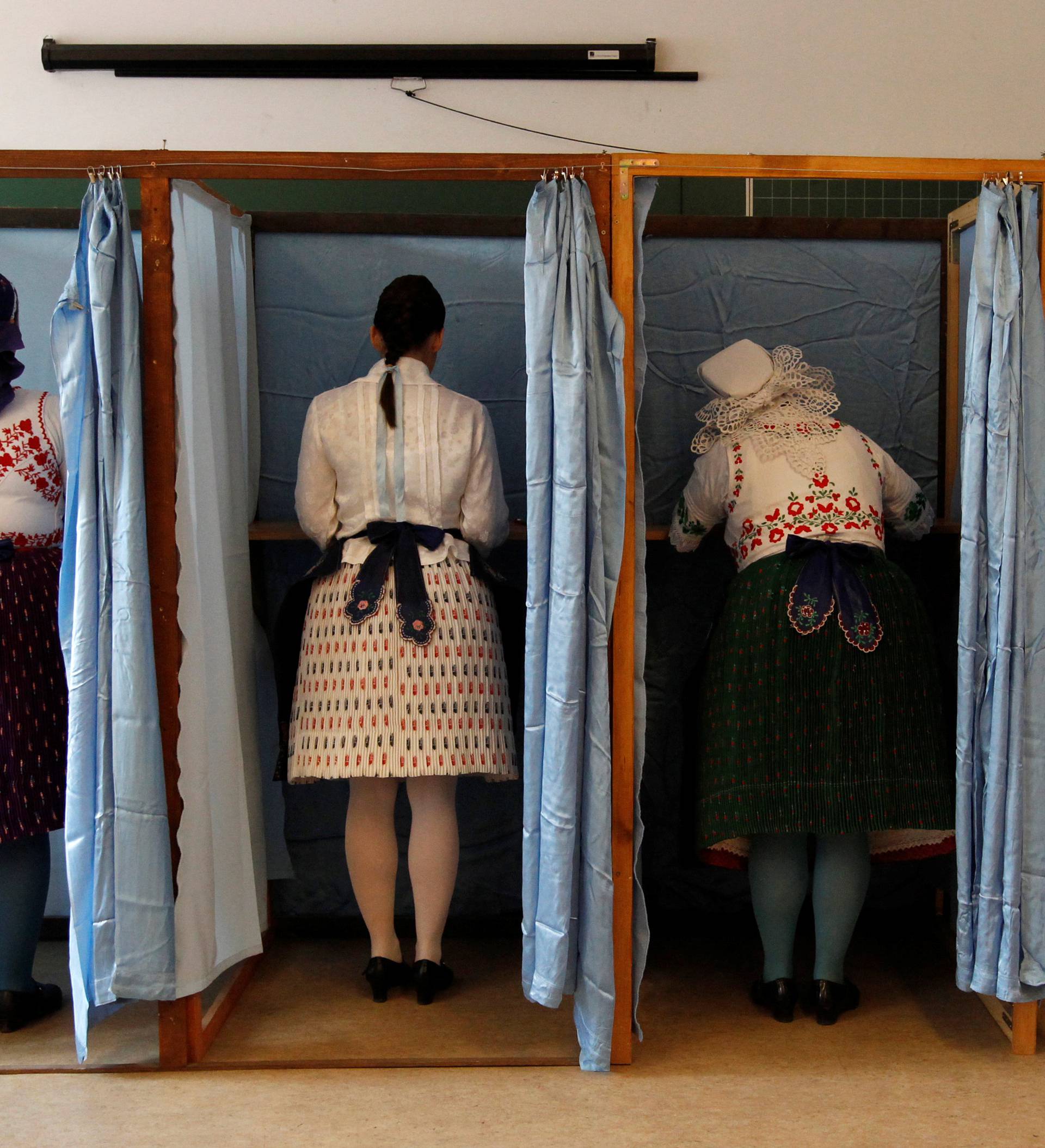 Hungarian women wearing traditional costum fill their ballot papers at a polling station during a referendum on EU migrant quotas in Veresegyhaz