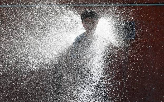 A boy cools off in a fountain during hot weather in central Brussels
