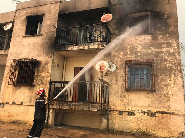 A firefighter uses a water hose after a fire broke out at a building in Ain al-Hammam village