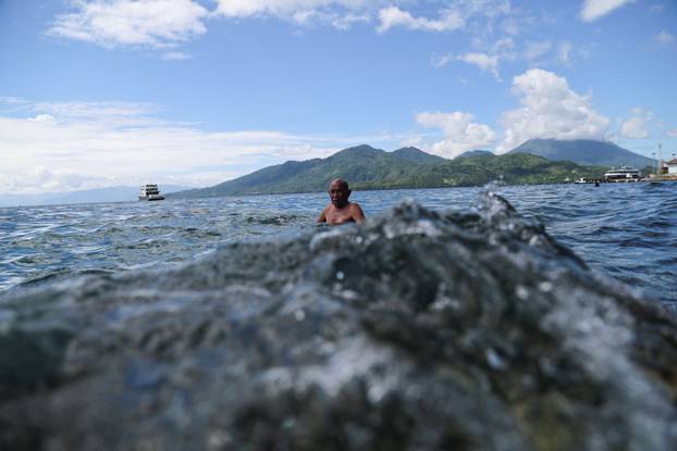 A man swims near Falajawa beach as the Meteorology, Climatology, and Geophysical agency issued a tsunami warning in Ternate