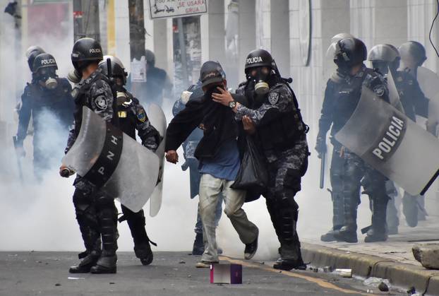 Police help a pedestrian overcome by tear gas as supporters of Nasralla clash with police during a protest caused by the delayed vote count for the presidential election in San Pedro Sula