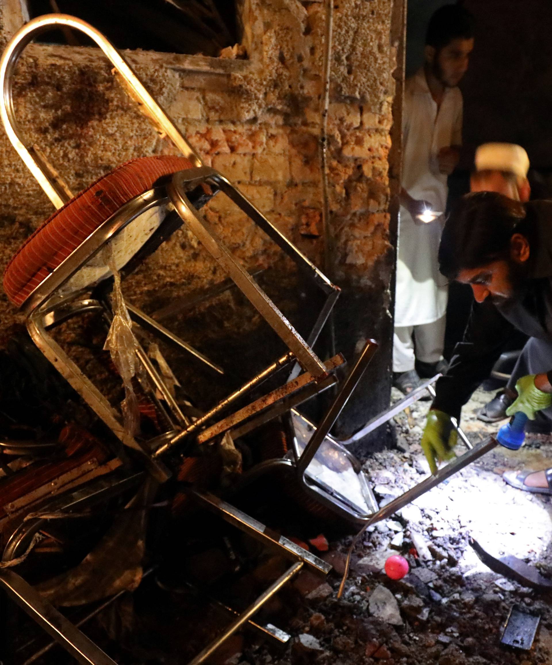 A police officer in plain clothes collects evidence from the site after a suicide attack during an election campaign meeting in Peshawar