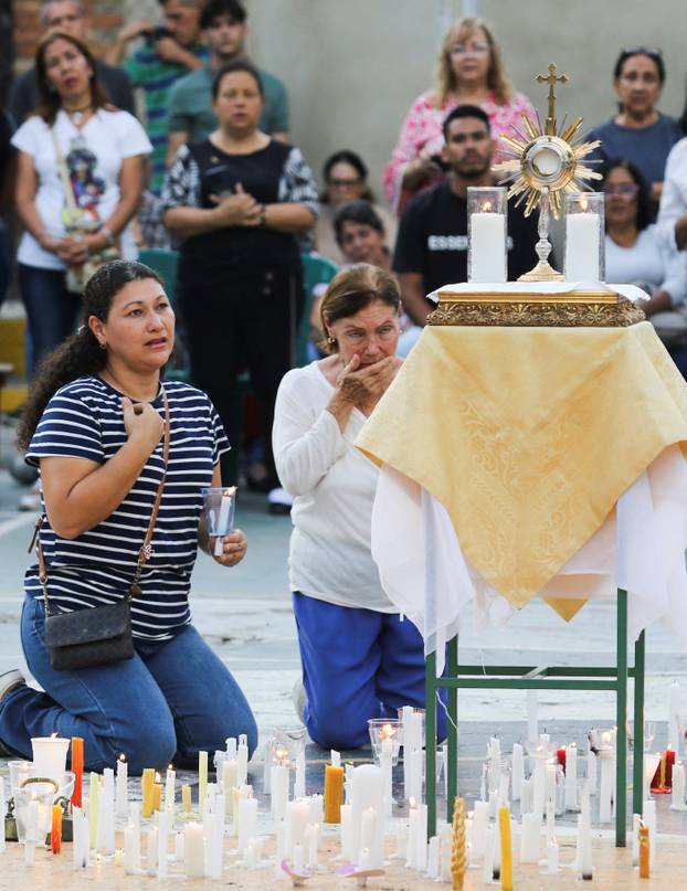 People take part in a candle vigil outside a church to pray for victims of earthquakes, in Valencia