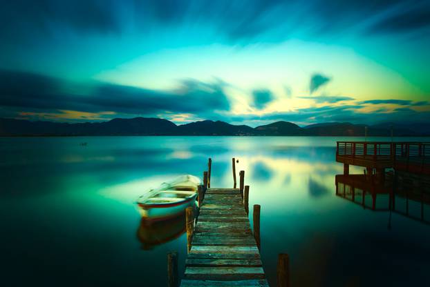 Wooden pier or jetty and a boat on a lake sunset. Versilia Tusca