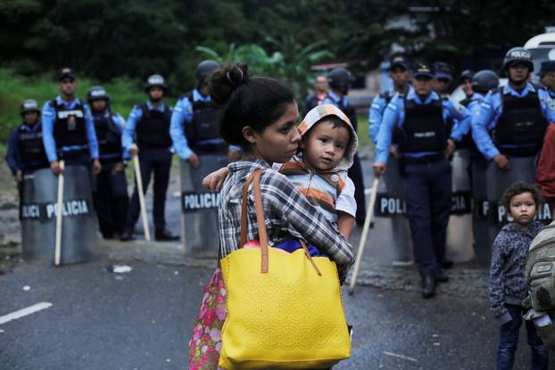 A Honduran migrant carries her baby in front of a police checkpoint near the Agua Caliente border while waiting to cross into Guatemala and join a caravan trying to reach the U.S., in the municipality of Ocotepeque