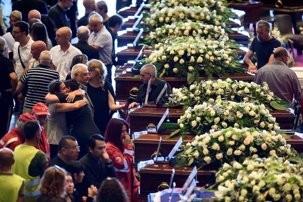 People mourn next to the coffins containing bodies of victims of the Genoa bridge collapse, at the Genoa Trade Fair and Exhibition Centre in Genoa