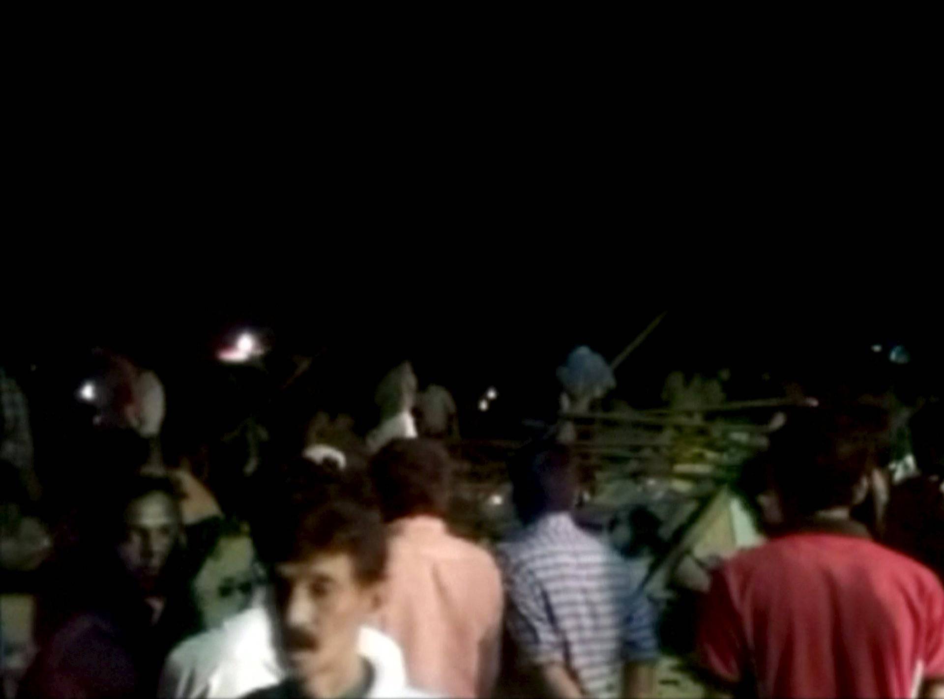 People gather at the debris of a temple where a fire broke out during a fireworks display in Kollam