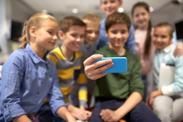 group of happy kids taking selfie with smartphone