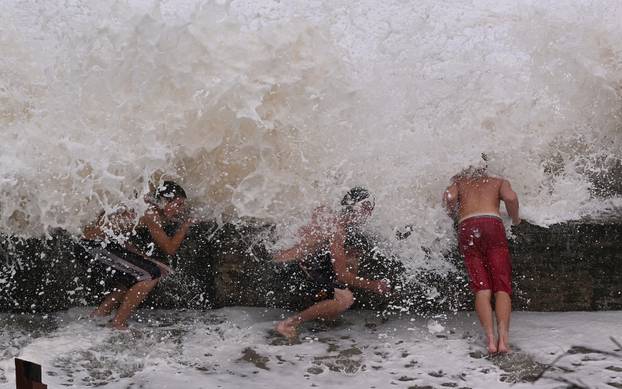 Boys shelter from waves behind a break-wall at Coolangatta ahead of Tropical Cyclone Alfred's landfall, on the Gold Coast