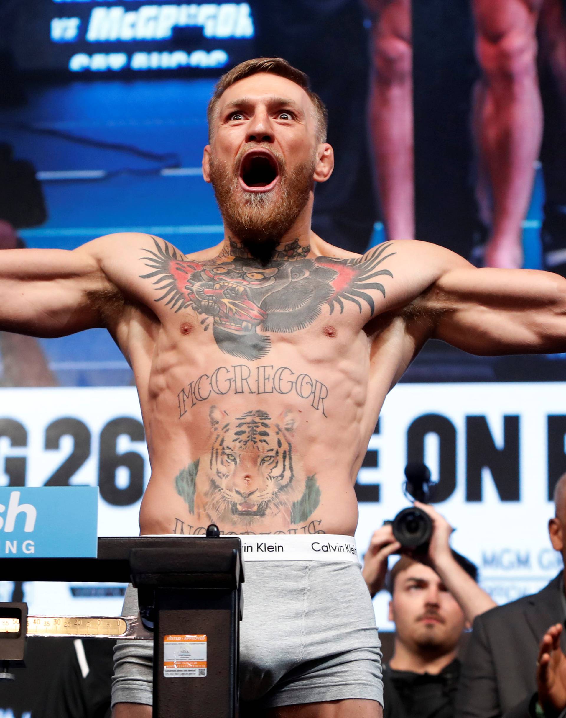 UFC lightweight champion Conor McGregor of Ireland poses on the scale during his official weigh-in at T-Mobile Arena in Las Vegas