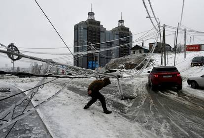 FILE PHOTO: A man walks under a damaged power pole covered with ice after freezing rain in Vladivostok