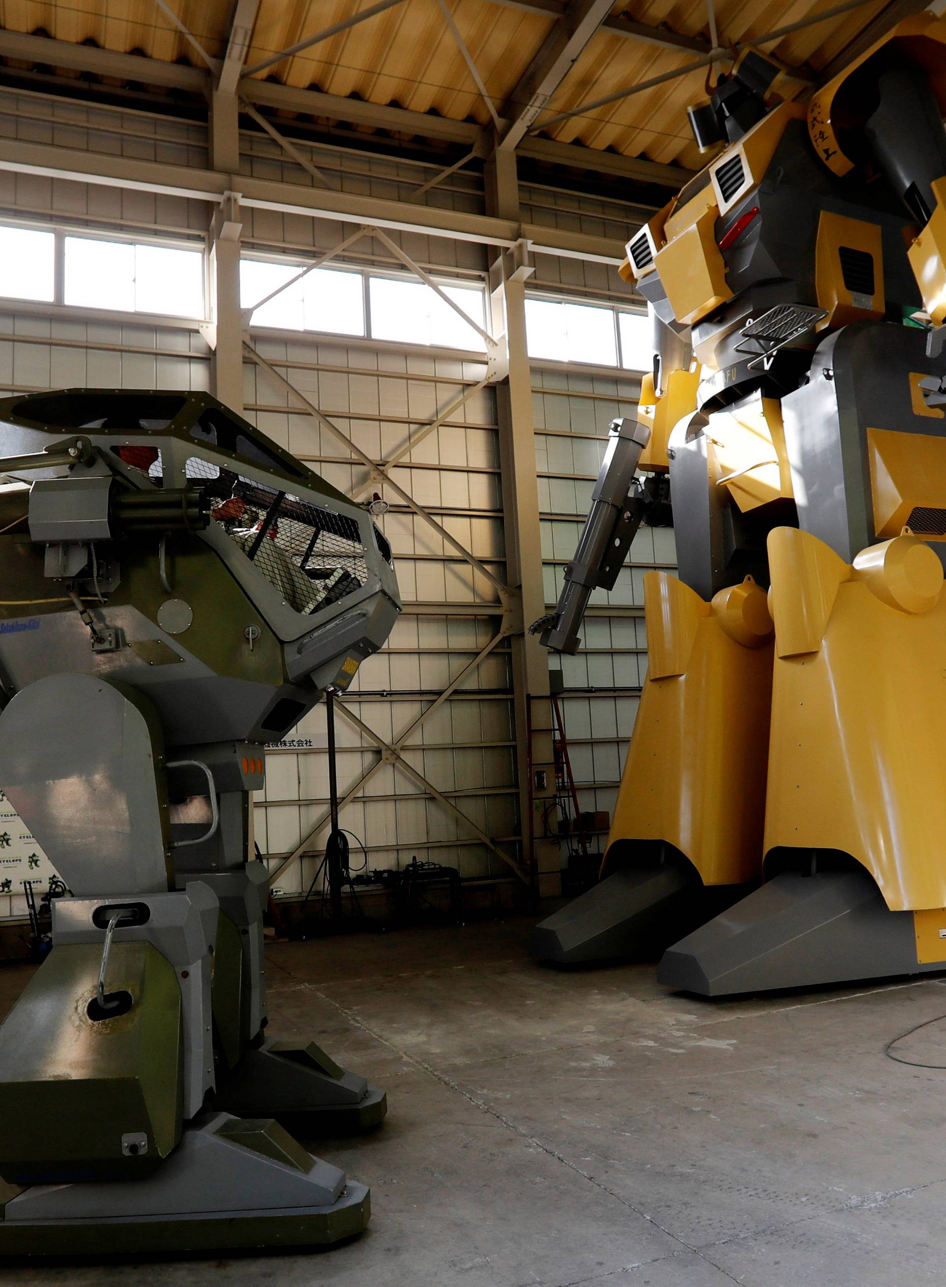 Sakakibara Kikai's engineer Masaaki Nagumo controls the bipedal robot Land Walker next to Mononofu during its demonstration at its factory in Shinto Village