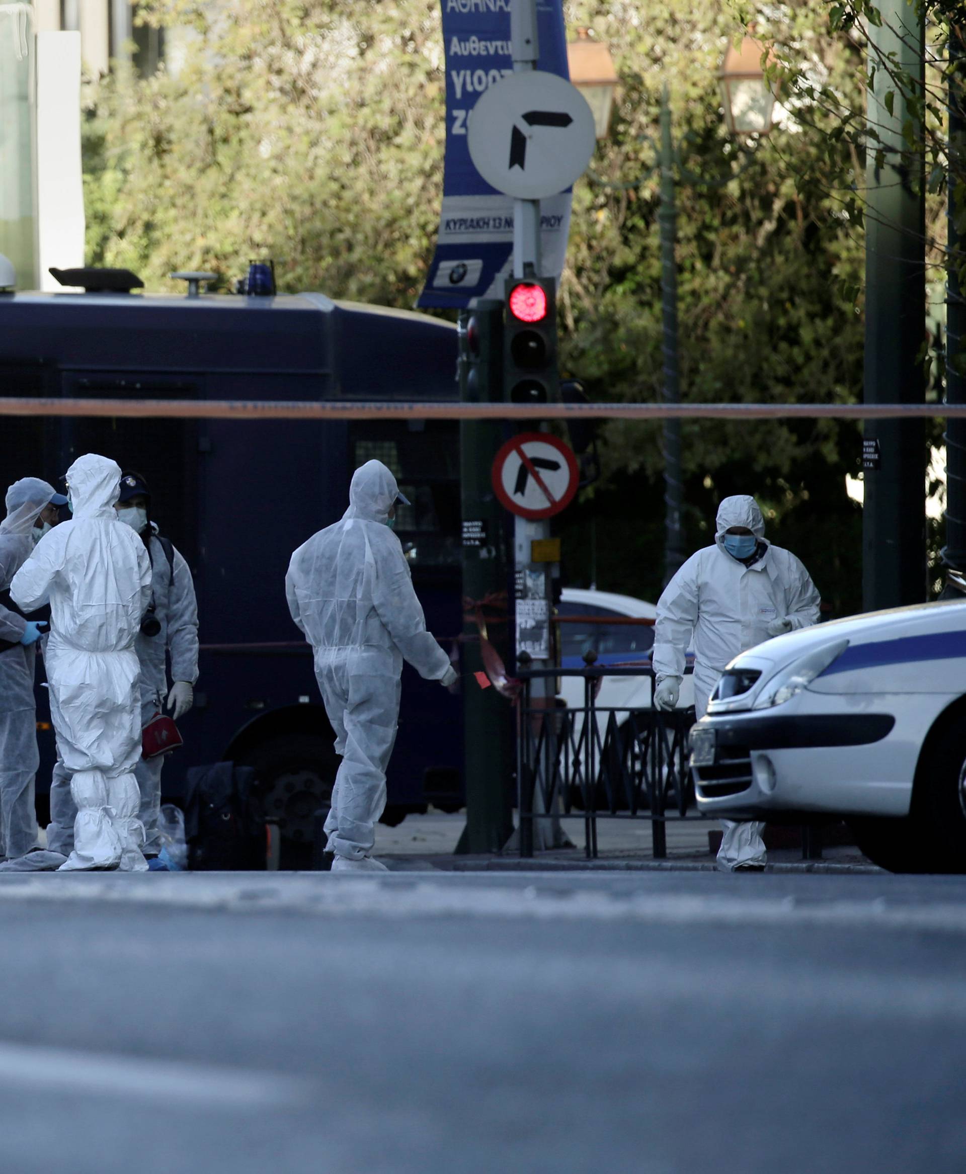Forensics experts search for evidence outside the French embassy, where unidentified attackers threw an explosive device causing a small blast, in Athens