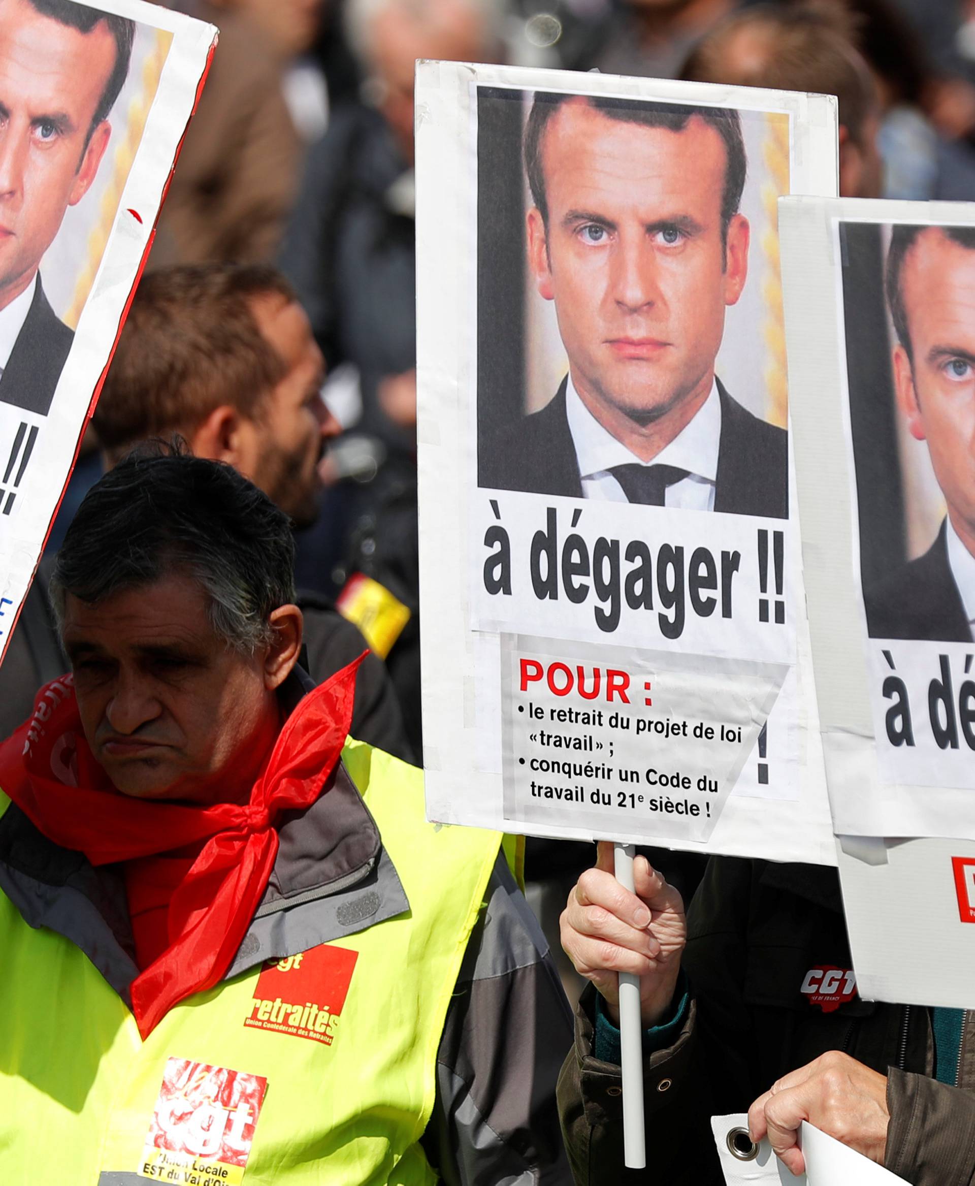 Demonstrators hold placards with portraits of French President Emmanuel Macron and the slogan "To clear out" during a national strike and protest against the government's labour reforms in Paris