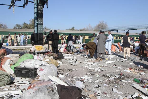 Plain-clothed police officers survey the site amid the debris after a bomb blast at a railway station in Quetta