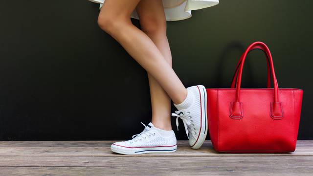 Beautiful fashionable big red handbag standing next to leggy woman