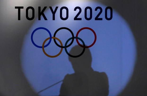 FILE PHOTO: Shadow of of Tokyo governor Yuriko Koike is seen on the logo of Tokyo 2020 Olympic games during the Olympic and Paralympic flag-raising ceremony at Tokyo Metropolitan Government Building in Tokyo