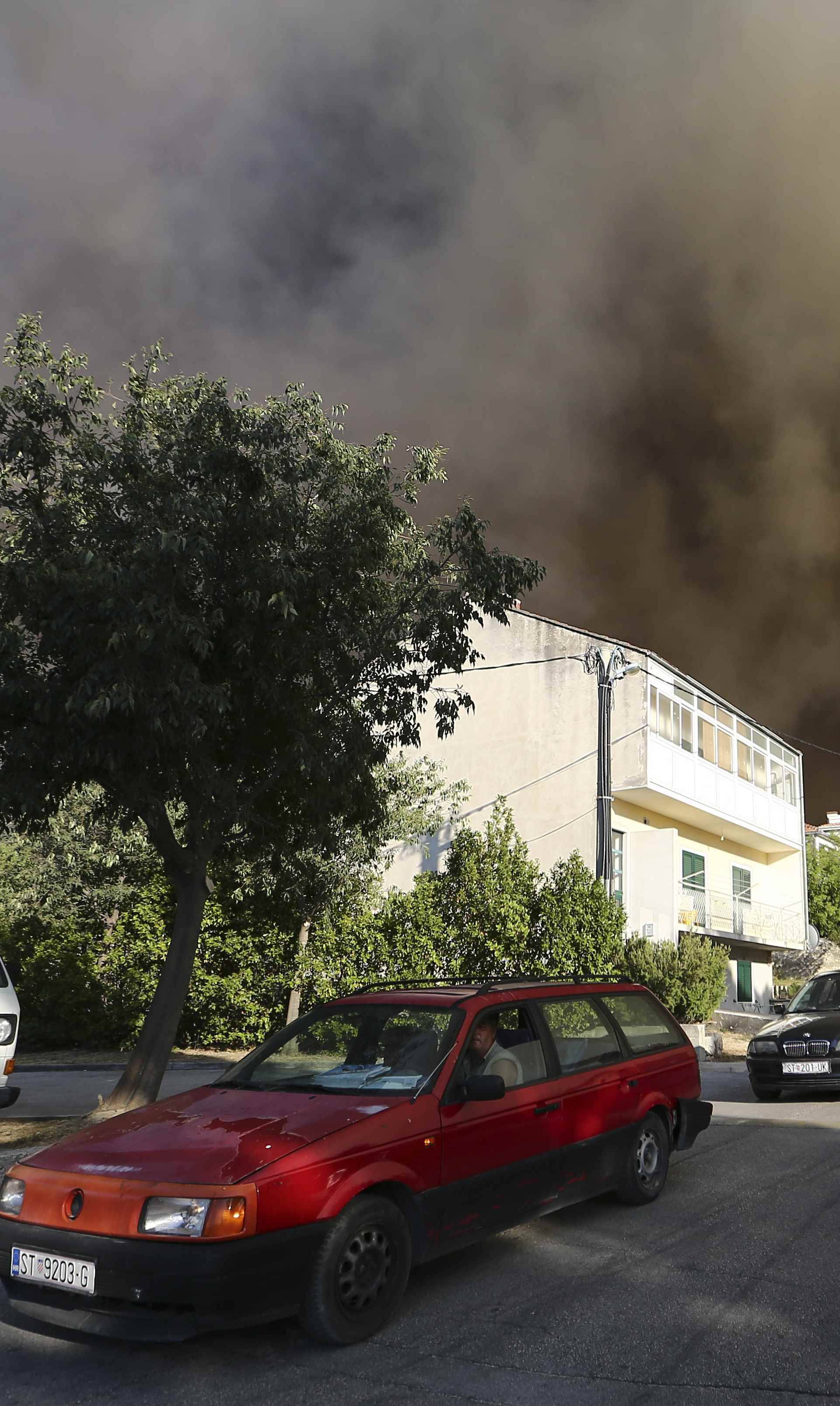 Smoke rises as local residents leave their homes due to a wildfire in the village of Mravinc near Split