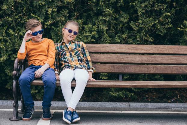 kids in sunglasses sitting together on bench at park