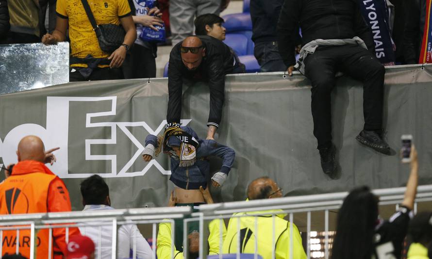 A Lyon fan helps another fan out of the stands as fans clash