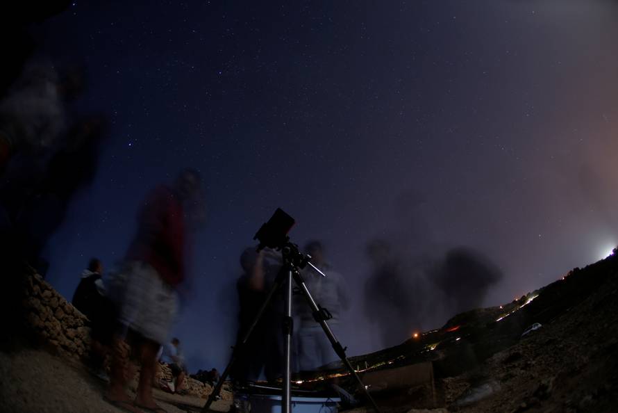 A man looks at the moon through a telescope during the Perseid meteor shower at Migra l-Ferha, outside the town of Rabat