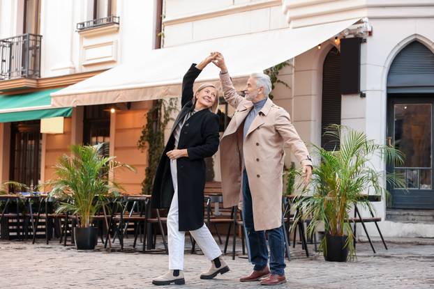 Affectionate senior couple dancing together on city street