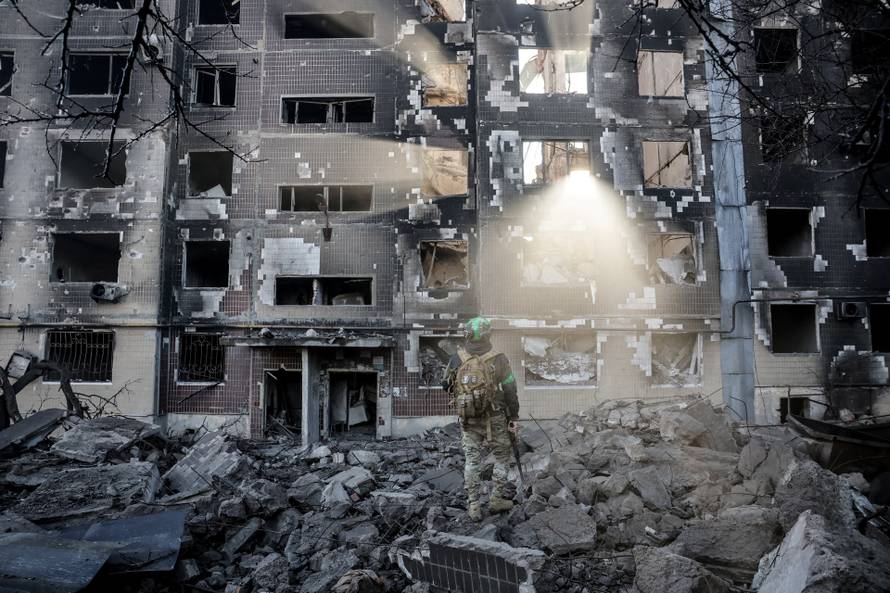 Ukrainian serviceman stands near an apartment building damaged by a Russian military strike in the frontline town of Kostiantynivka