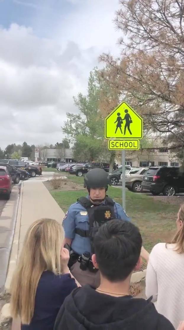 A police officer reassures people waiting outside near the STEM School during a shooting incident in Highlands Ranch, Colorado, U.S. in this May 7, 2019 still frame obtained via social media video