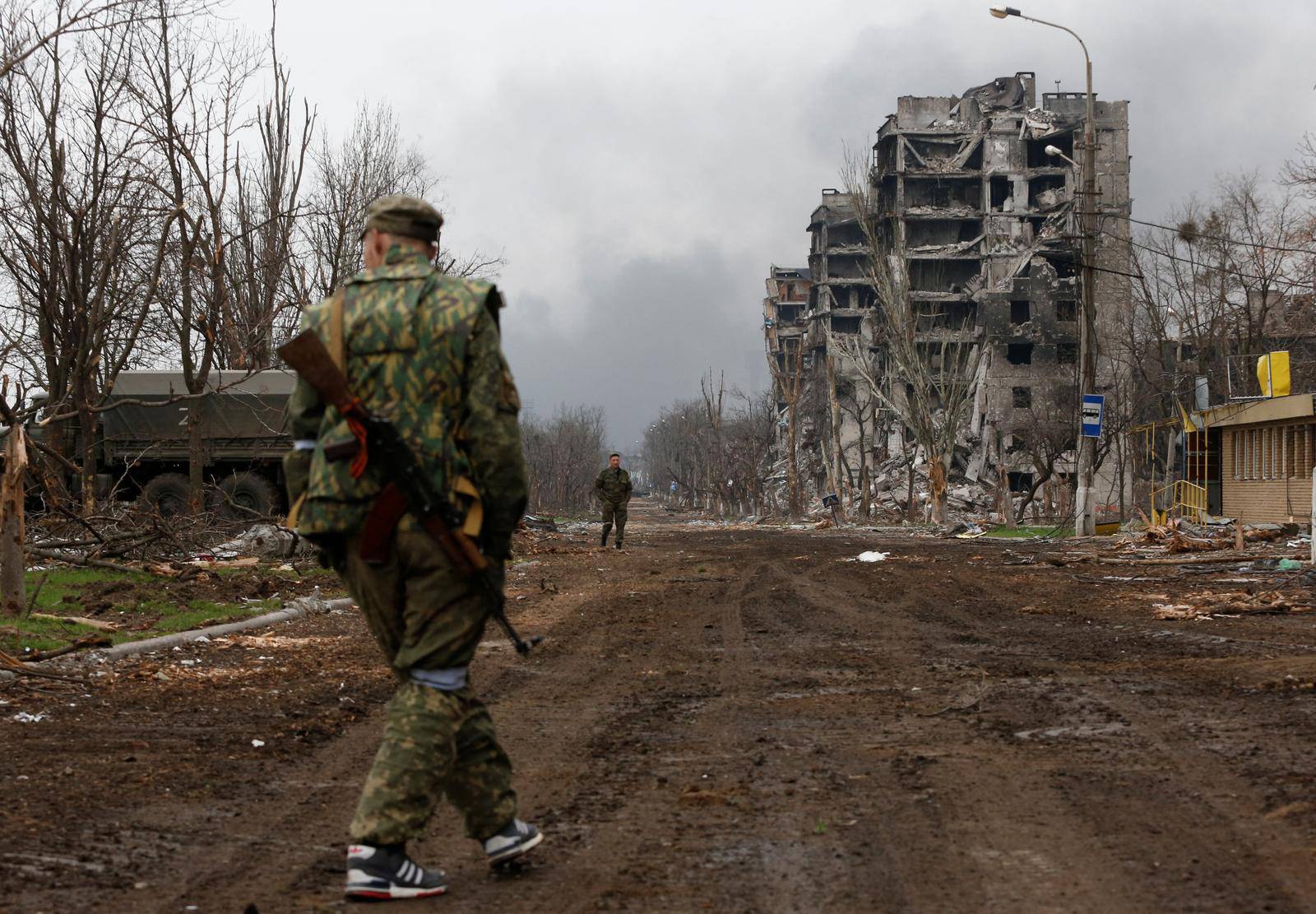 Service members of pro-Russian troops walk in the street during fighting in Mariupol