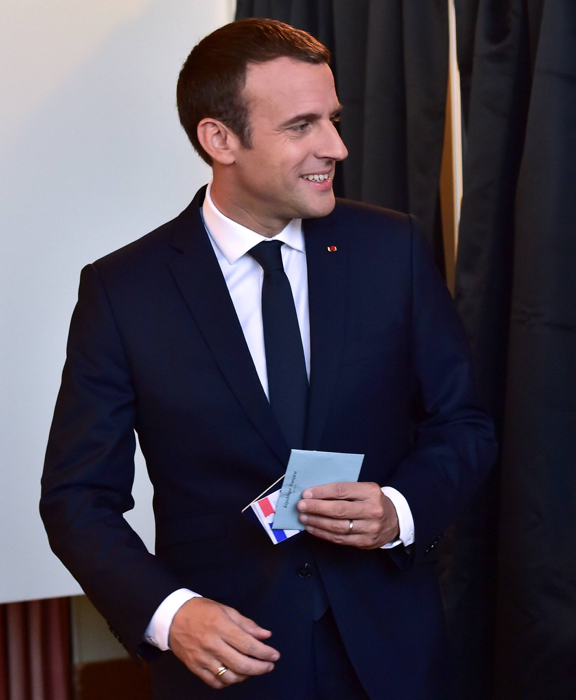 French President Emmanuel Macron hold his ballot before voting at a polling station in the second round parliamentary elections in Le Touquet