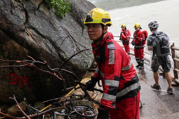 A firefighter moves a fallen branch after Super Typhoon Ragasa passes, as he assesses damage from storm surge and flooding, in Hong Kong
