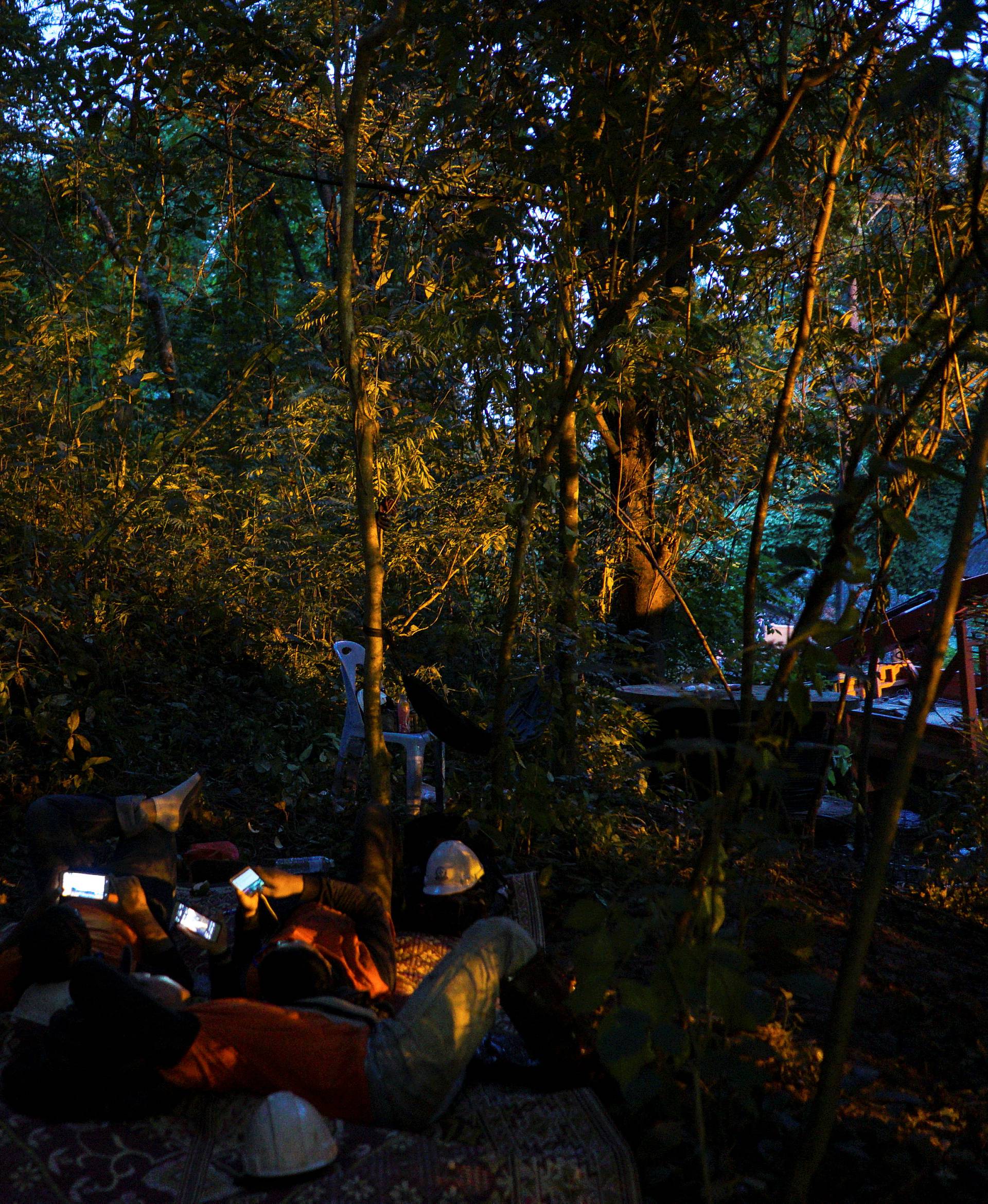 Rescue workers use mobile phones as they take a short break near the Tham Luang cave in the northern province of Chiang Rai