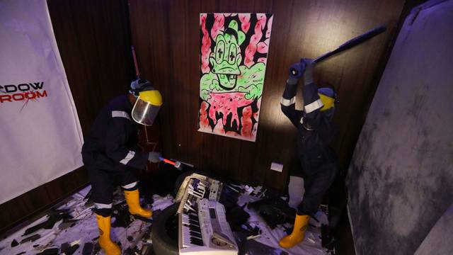 People smash a musical keyboard at the Shadow rage room, a place where people can destroy objects to vent anger, in Lagos