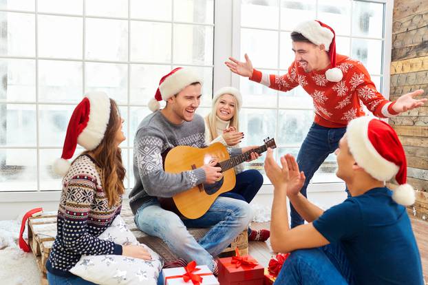 A group of friends with  guitar and singing at home on Christmas