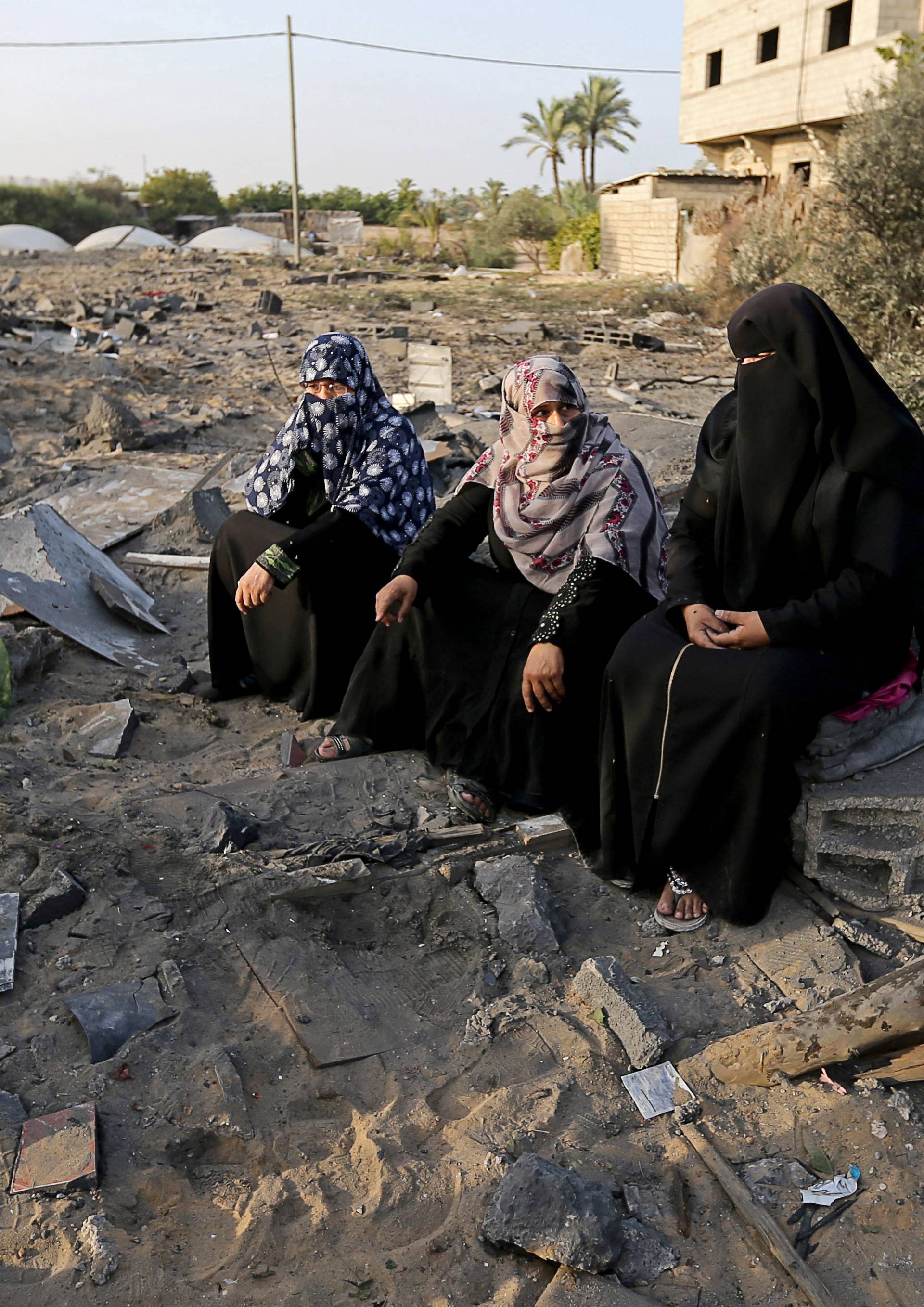 Palestinian women sit near the remains of a house destroyed in an Israeli air strike in the southern Gaza Strip