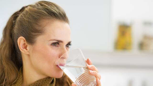 young housewife drinking water in kitchen