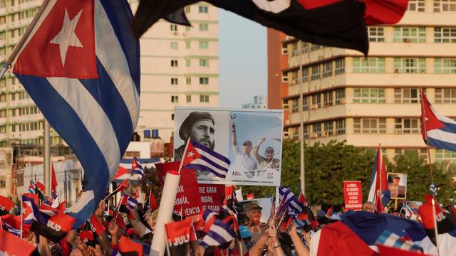 People carry a poster with photographs of Fidel Castro, Miguel Diaz-Canel and Raul Castro during a rally in Havana